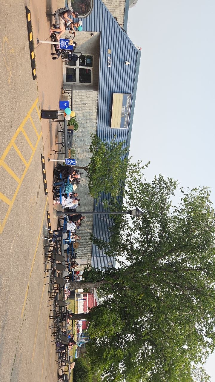 Neighbours sitting at tables outside the Whitehorn Community Centre on a summer afternoon