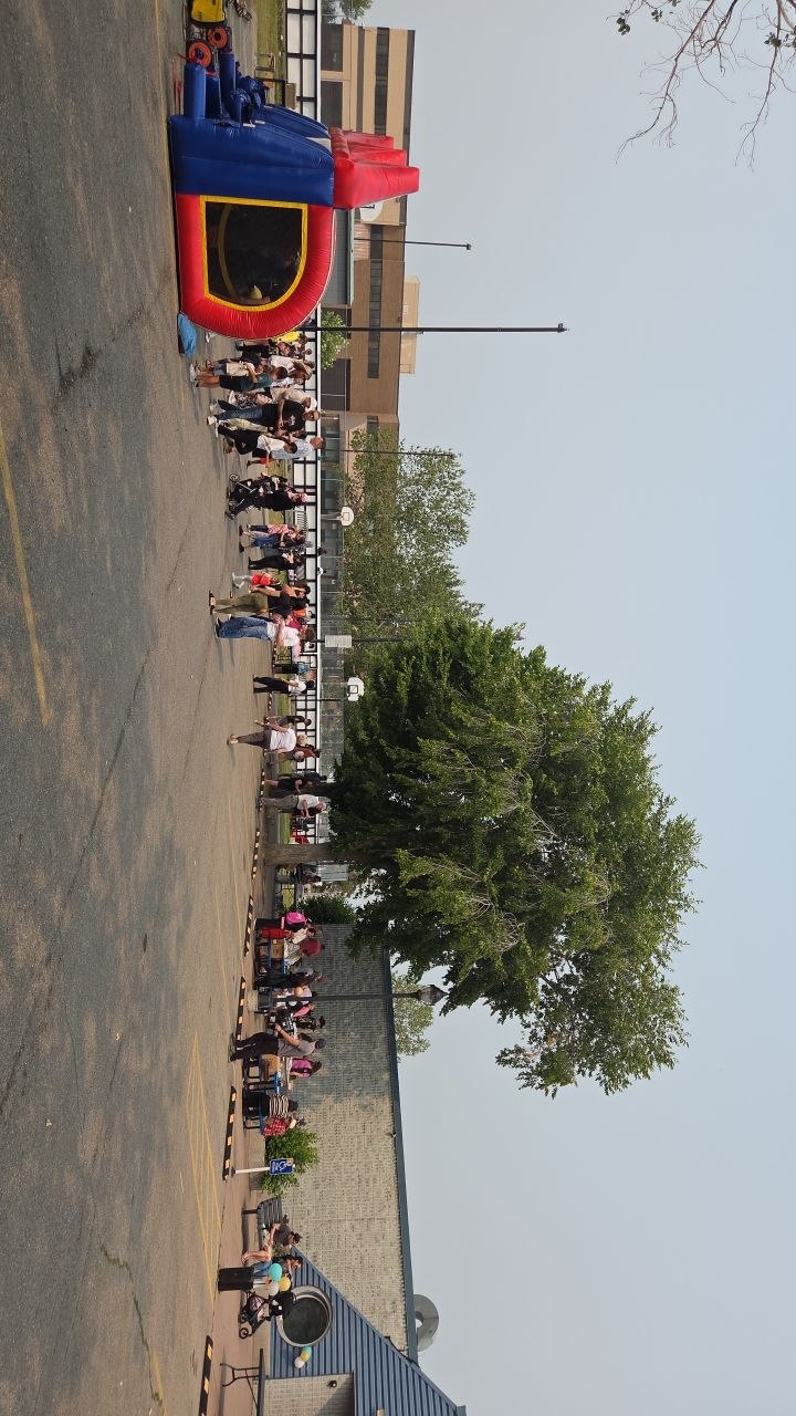 Families and children gathered in the lot at the 50th anniversary party, with a bouncy castle and games